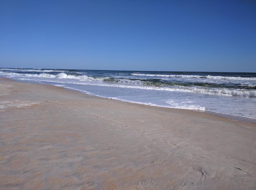 Photo of a beach with waves and sand.
