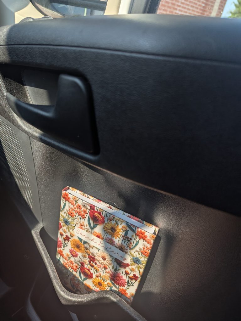 Photo of notebook tucked inside of a car's seat pocket.