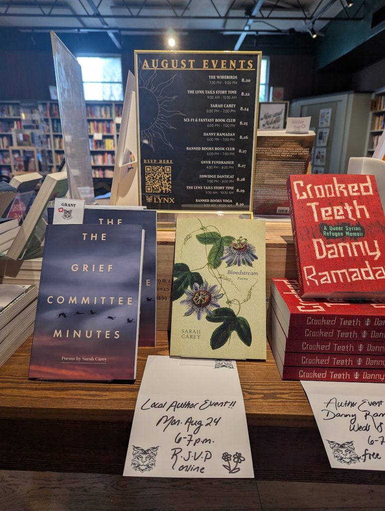 A bookstore display showing both of Sarah Carey's poetry books, The Grief Committee Minutes and Bloodstream, right next to each other in stacks at The Lynx Books.